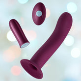 A maroon-colored, cylindrical Femme Funn Versa S - Sleeve and Bullet Vibrator with a curved tip and suction base is displayed in front of a soft-focus background of pastel lights. Accompanying it are a smaller, oval-shaped remote control and a short, bullet-shaped accessory designed for G-spot stimulation with 7 powerful vibration modes.